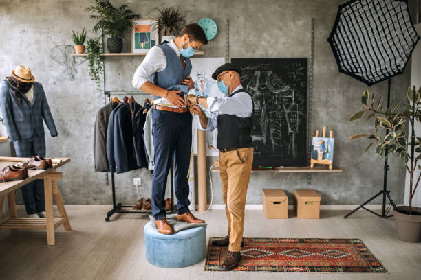 Thợ may đang đo vest cho khách tại tiệm may cao cấp